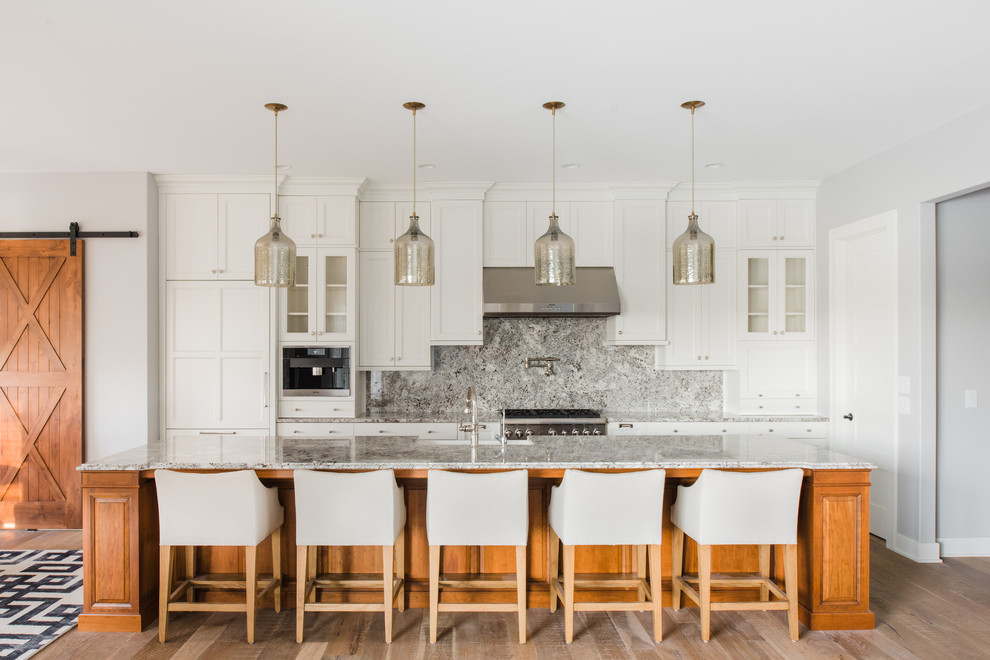 Inspiration for a transitional light wood floor kitchen remodel with shaker cabinets, white cabinets, gray backsplash, stainless steel appliances and an island