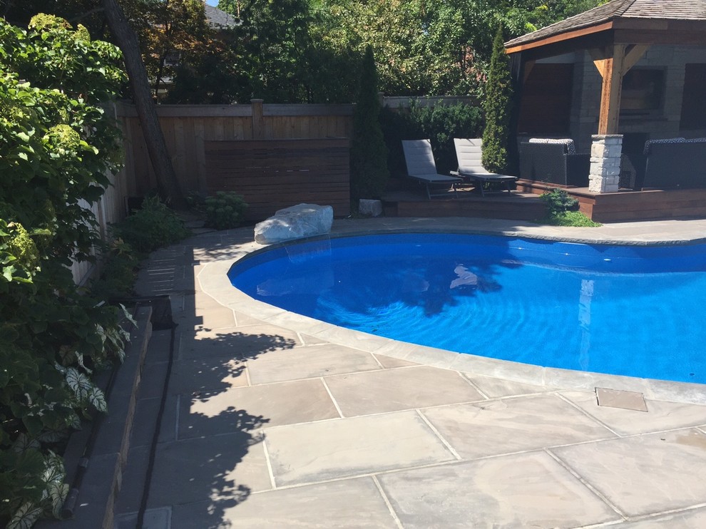 Inspiration for a mid-sized traditional backyard kidney-shaped lap pool in Toronto with a water feature and natural stone pavers.