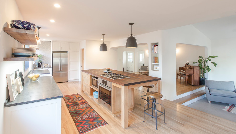 Contemporary eat-in kitchen in Santa Barbara with a farmhouse sink, white cabinets, stainless steel appliances, light hardwood floors and with island.
