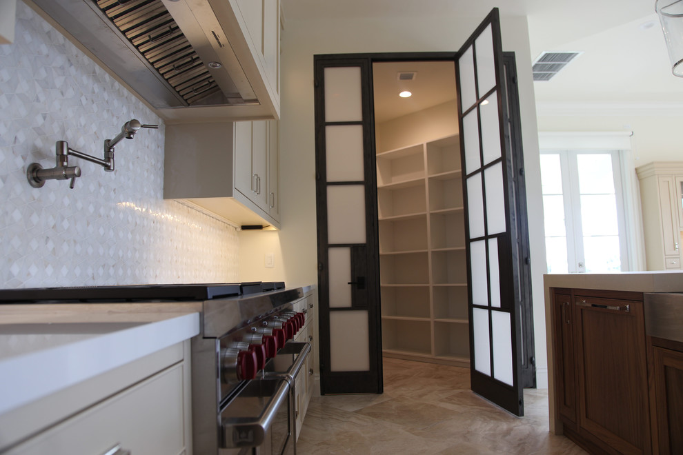 This is an example of a large contemporary kitchen pantry in Miami with shaker cabinets, beige cabinets, quartz benchtops, grey splashback, marble splashback, stainless steel appliances, with island, beige floor and white benchtop.