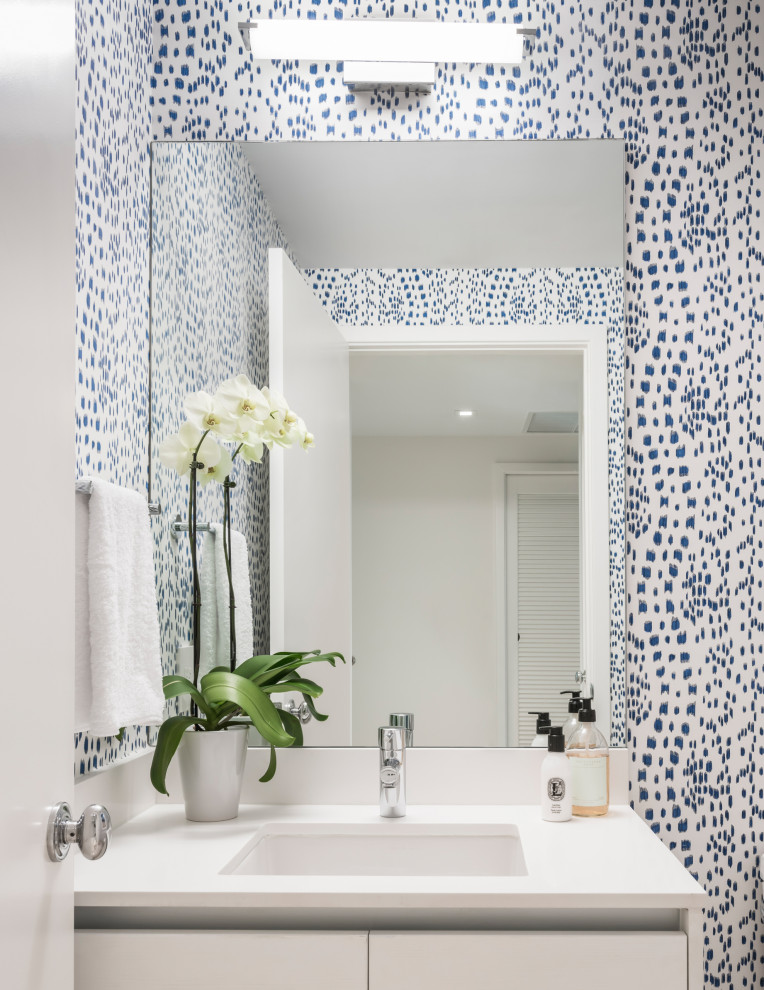 This is an example of a small contemporary cloakroom in Miami with flat-panel cabinets, white cabinets, a two-piece toilet, blue tiles, porcelain flooring, a built-in sink, quartz worktops, beige floors, white worktops, a built in vanity unit and wallpapered walls.