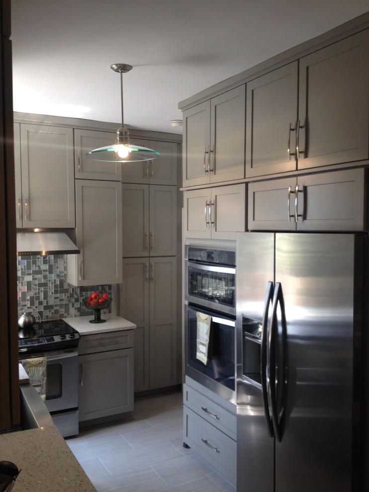 This is an example of a small transitional u-shaped kitchen pantry in Charlotte with no island, raised-panel cabinets, beige cabinets, recycled glass benchtops, grey splashback, glass tile splashback, stainless steel appliances, a farmhouse sink and porcelain floors.
