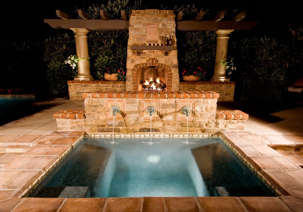 This is an example of a small mediterranean backyard patio in Los Angeles with a water feature, tile and a pergola.