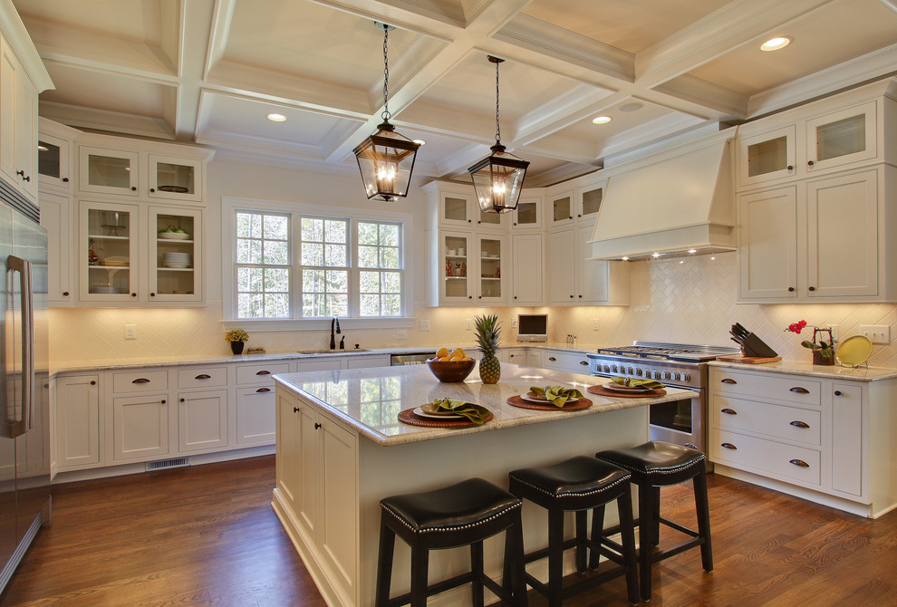 Photo of a traditional u-shaped kitchen in Raleigh with shaker cabinets, white cabinets, white splashback and stainless steel appliances.