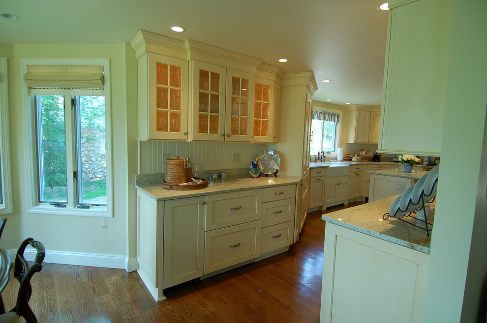 Mid-sized beach style eat-in kitchen in Boston with a farmhouse sink, recessed-panel cabinets, yellow cabinets, granite benchtops, white splashback, panelled appliances, medium hardwood floors and with island.