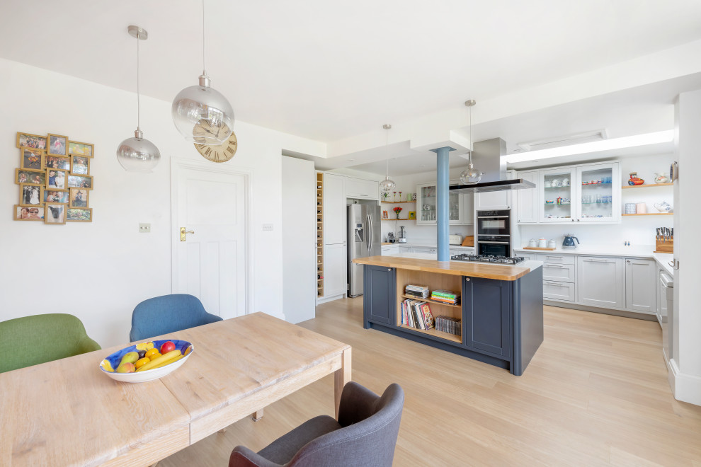 Esempio di una grande sala da pranzo aperta verso la cucina contemporanea con pareti bianche, parquet chiaro e pavimento marrone