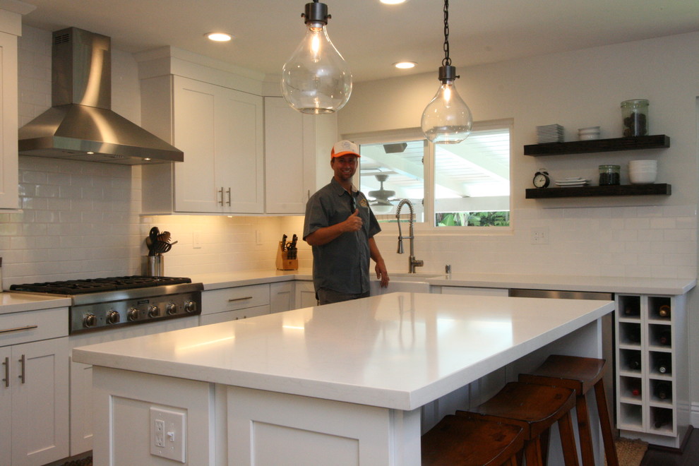 Inspiration for a large transitional u-shaped dark wood floor eat-in kitchen remodel in Orange County with a farmhouse sink, shaker cabinets, white cabinets, quartz countertops, white backsplash, ceramic backsplash, stainless steel appliances and an island