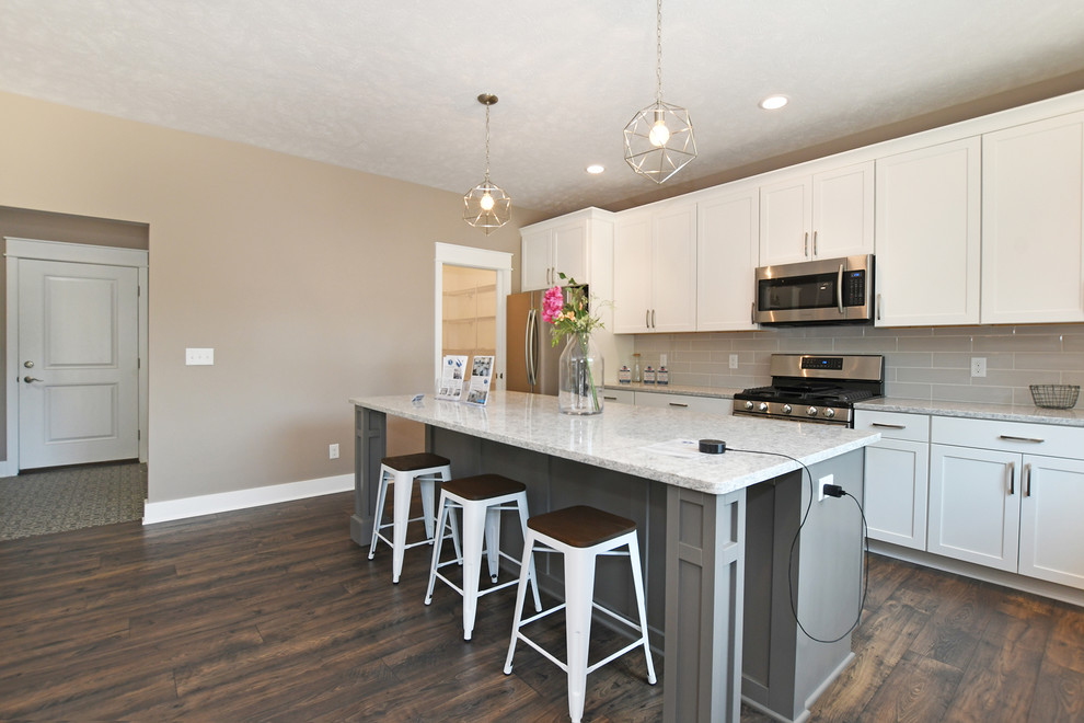 Inspiration for a large galley vinyl floor and brown floor eat-in kitchen remodel in Grand Rapids with an undermount sink, shaker cabinets, white cabinets, quartzite countertops, beige backsplash, subway tile backsplash, stainless steel appliances, an island and gray countertops