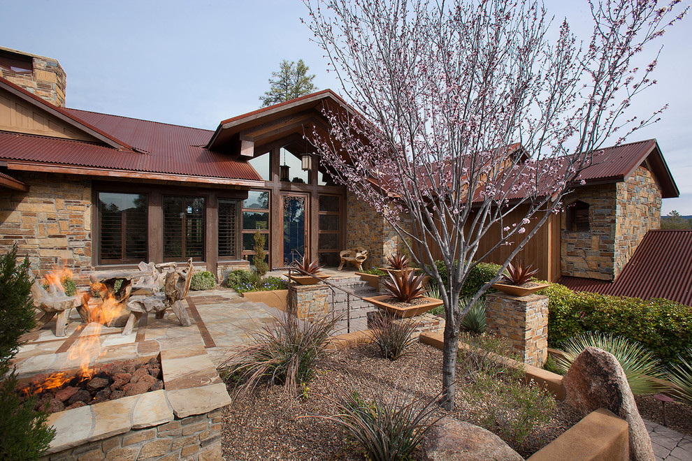 This is an example of a mid-sized country split-level brown exterior in Phoenix with stone veneer and a gable roof.