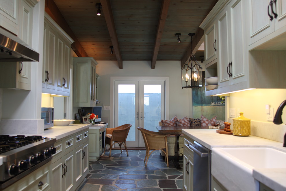 Example of a small mountain style galley multicolored floor eat-in kitchen design in Los Angeles with a farmhouse sink, stainless steel appliances, recessed-panel cabinets, white cabinets, marble countertops, white backsplash, stone tile backsplash, no island and white countertops