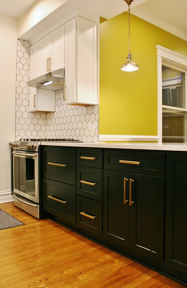 Small transitional galley medium tone wood floor and brown floor eat-in kitchen photo in Chicago with an undermount sink, shaker cabinets, white cabinets, quartz countertops, white backsplash, porcelain backsplash, stainless steel appliances and an island
