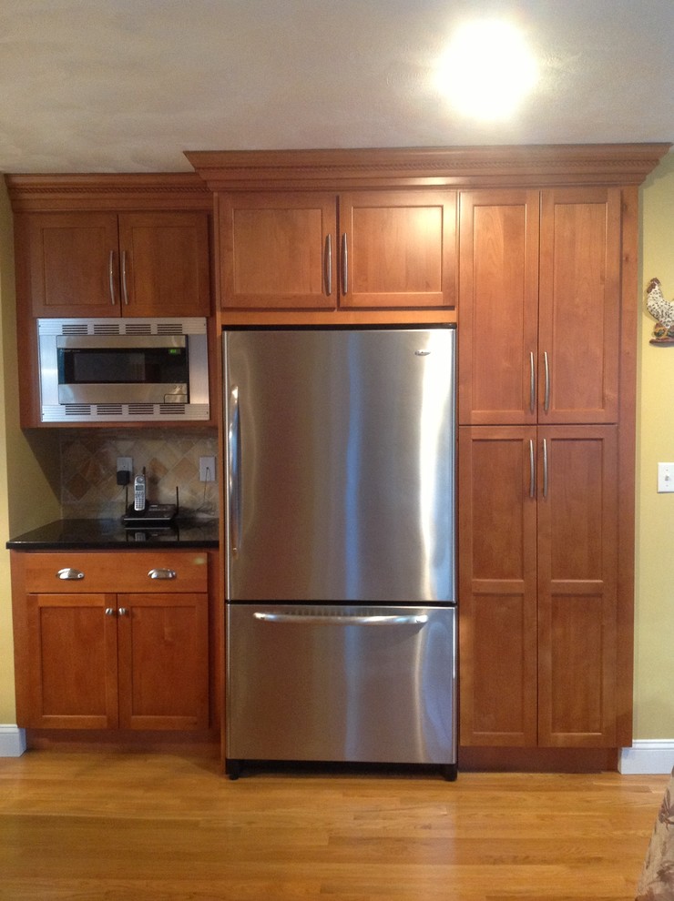 Example of a mid-sized transitional l-shaped medium tone wood floor eat-in kitchen design in Boston with an undermount sink, shaker cabinets, medium tone wood cabinets, granite countertops, stone tile backsplash, stainless steel appliances and an island