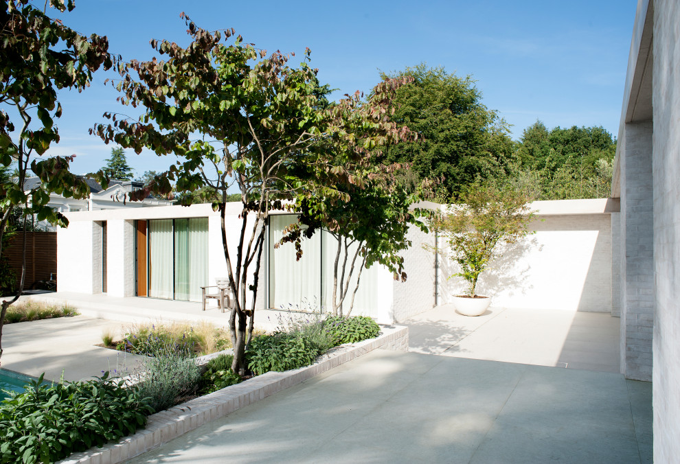 Bild på en mycket stor minimalistisk trädgård i full sol pallkragar på sommaren, med naturstensplattor