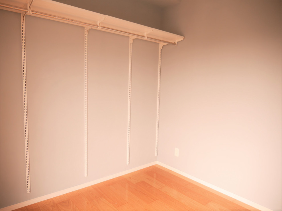 This is an example of a mid-sized gender-neutral walk-in wardrobe in Other with plywood floors, brown floor and wallpaper.