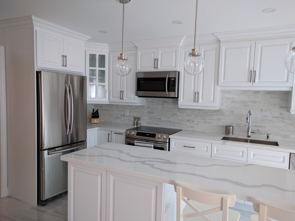 Inspiration for a mid-sized transitional l-shaped kitchen remodel in Toronto with an undermount sink, raised-panel cabinets, white cabinets, stainless steel appliances and an island
