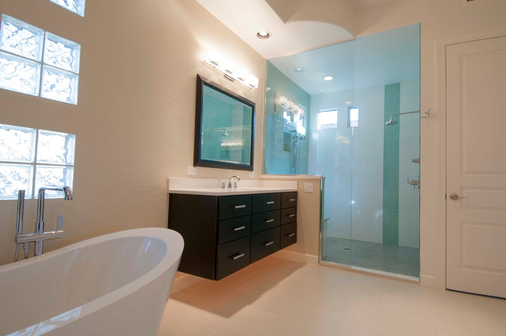 Photo of a large modern master bathroom in Phoenix with a drop-in sink, raised-panel cabinets, dark wood cabinets, laminate benchtops, a freestanding tub, a double shower, a one-piece toilet, white tile, matchstick tile, white walls and ceramic floors.
