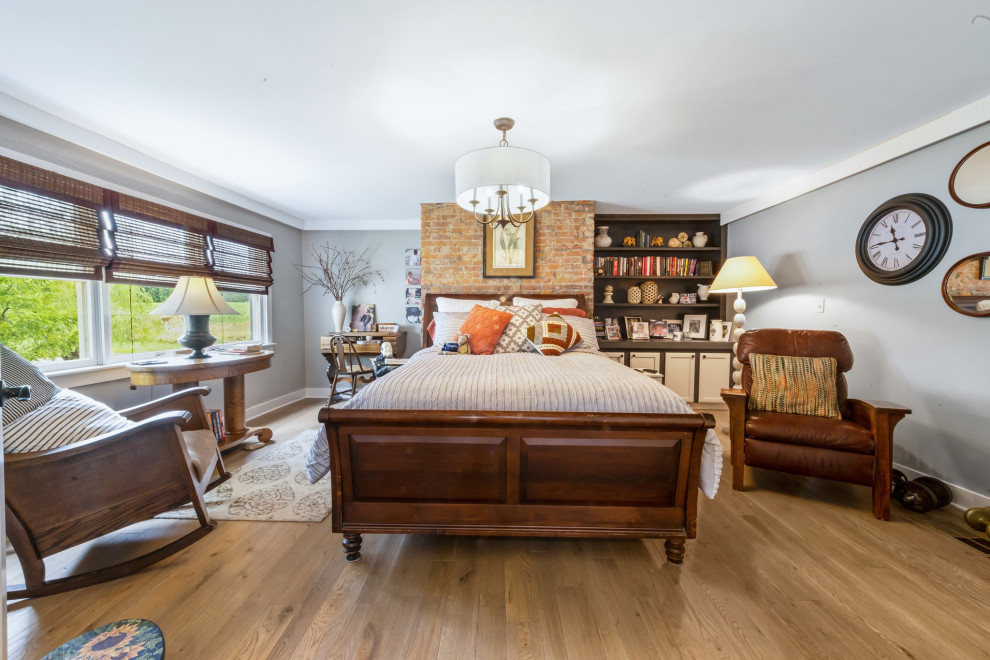 Mid-sized country master bedroom in Cincinnati with grey walls, medium hardwood floors, beige floor and brick walls.