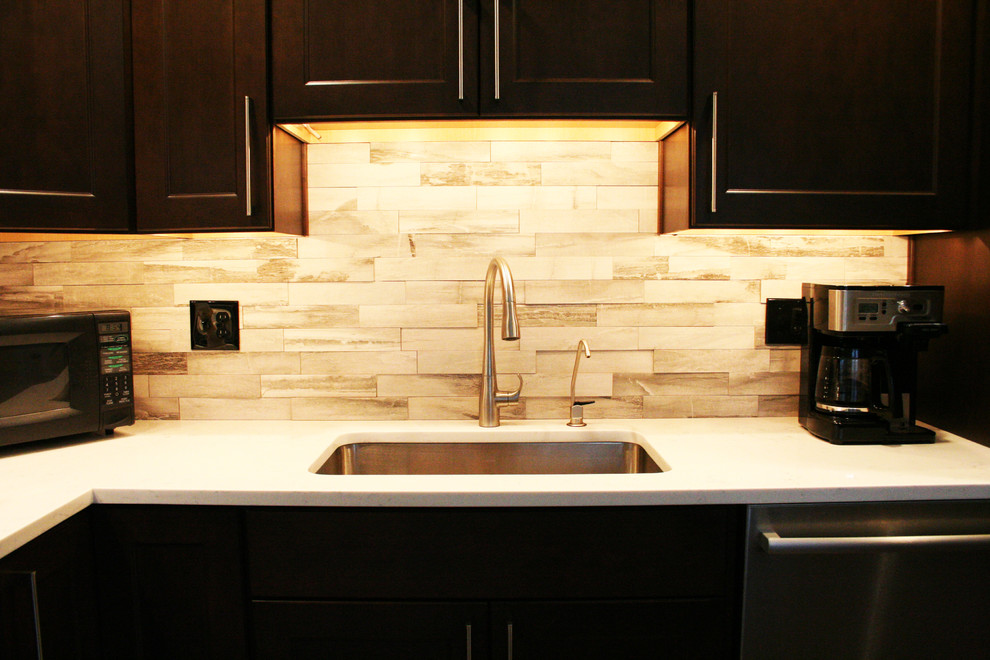 Mid-sized transitional l-shaped eat-in kitchen photo in DC Metro with flat-panel cabinets, dark wood cabinets, quartzite countertops, gray backsplash, stone tile backsplash, stainless steel appliances and an island