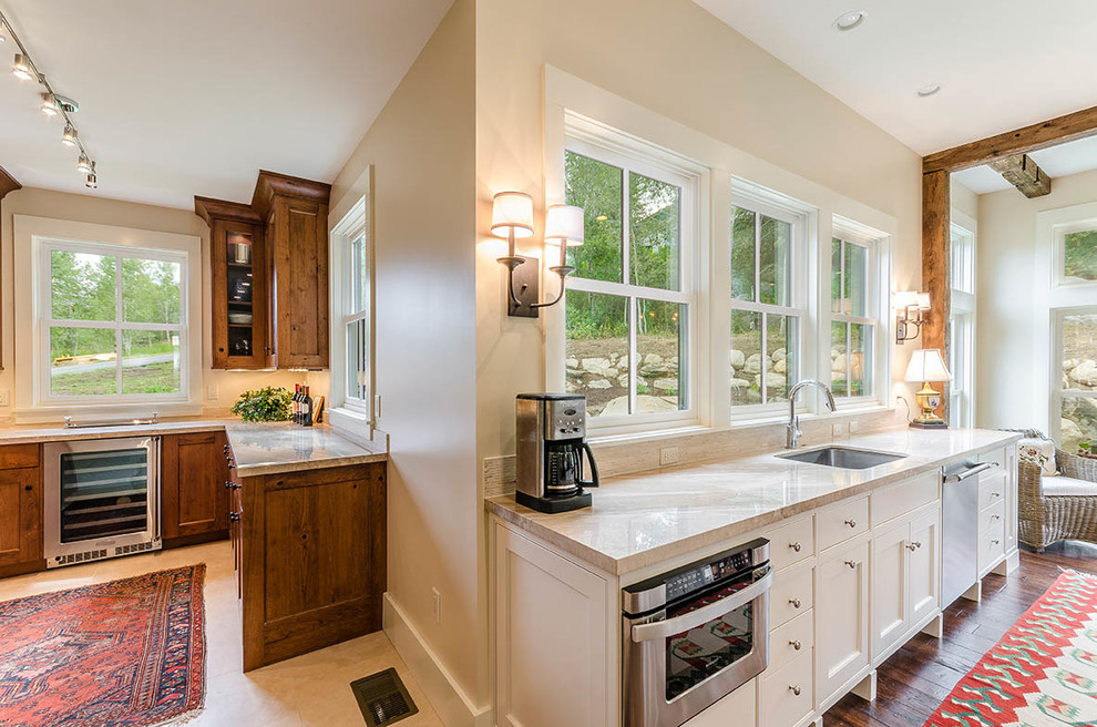 Huge transitional l-shaped dark wood floor and brown floor eat-in kitchen photo with an undermount sink, shaker cabinets, white cabinets, wood countertops, gray backsplash, matchstick tile backsplash, stainless steel appliances and an island