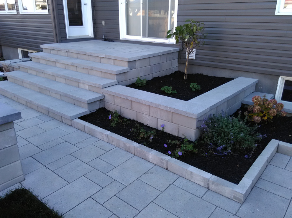 This is an example of a large modern backyard patio in Ottawa with a container garden, concrete pavers and an awning.