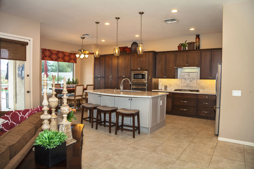 Transitional ceramic tile eat-in kitchen photo in Phoenix with an undermount sink, recessed-panel cabinets, dark wood cabinets, quartzite countertops, gray backsplash, stone tile backsplash, stainless steel appliances and an island