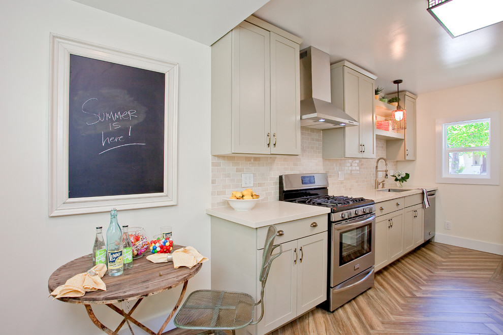 Small arts and crafts galley kitchen in San Francisco with an integrated sink, shaker cabinets, grey cabinets, quartz benchtops, beige splashback, stone tile splashback, stainless steel appliances and porcelain floors.