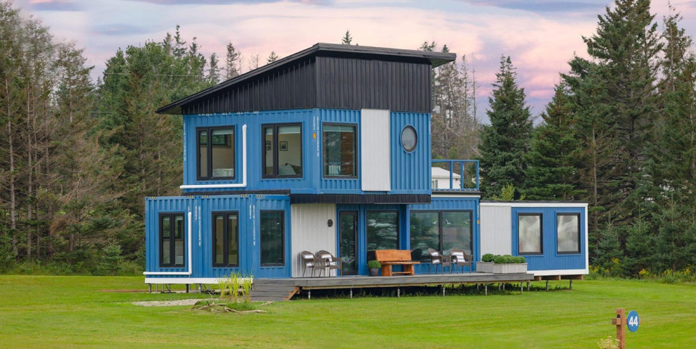 Design ideas for a small modern two-storey blue exterior in Other with metal siding and a black roof.