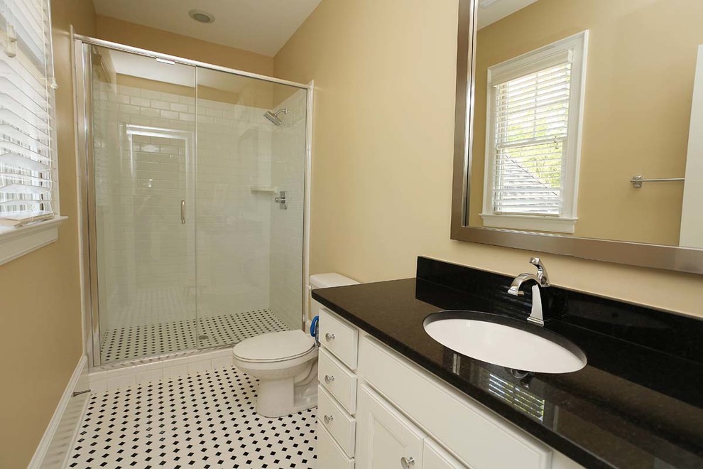 Photo of a mid-sized traditional 3/4 bathroom in Charlotte with an undermount sink, recessed-panel cabinets, white cabinets, engineered quartz benchtops, an alcove shower, a one-piece toilet, white tile, subway tile, beige walls and mosaic tile floors.