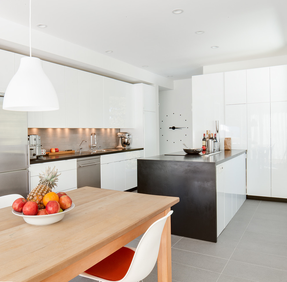Inspiration for a mid-sized scandinavian eat-in kitchen in Salt Lake City with a double-bowl sink, flat-panel cabinets, white cabinets, onyx benchtops, grey splashback, stone tile splashback, stainless steel appliances, travertine floors and with island.