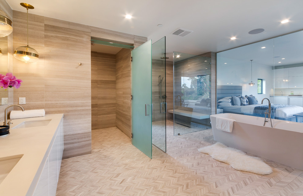Contemporary master bathroom in Los Angeles with flat-panel cabinets, white cabinets, a freestanding tub, a curbless shower, beige tile, beige walls, an undermount sink, beige floor and a hinged shower door.