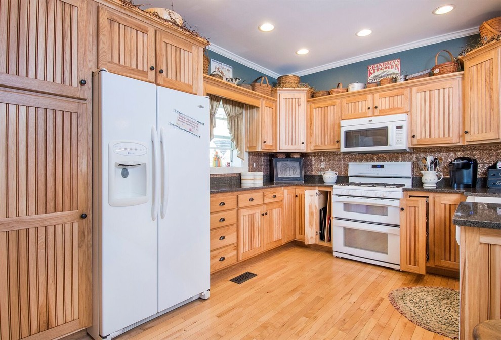 Example of a mid-sized mountain style u-shaped light wood floor and brown floor eat-in kitchen design in Cincinnati with a farmhouse sink, recessed-panel cabinets, light wood cabinets, granite countertops, metallic backsplash, ceramic backsplash, white appliances, a peninsula and gray countertops