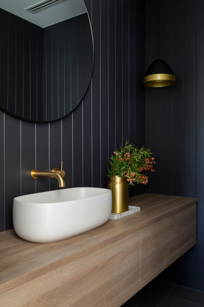 Inspiration pour un WC et toilettes design en bois clair avec un placard à porte plane, un mur noir, une vasque, un plan de toilette en bois et meuble-lavabo suspendu.