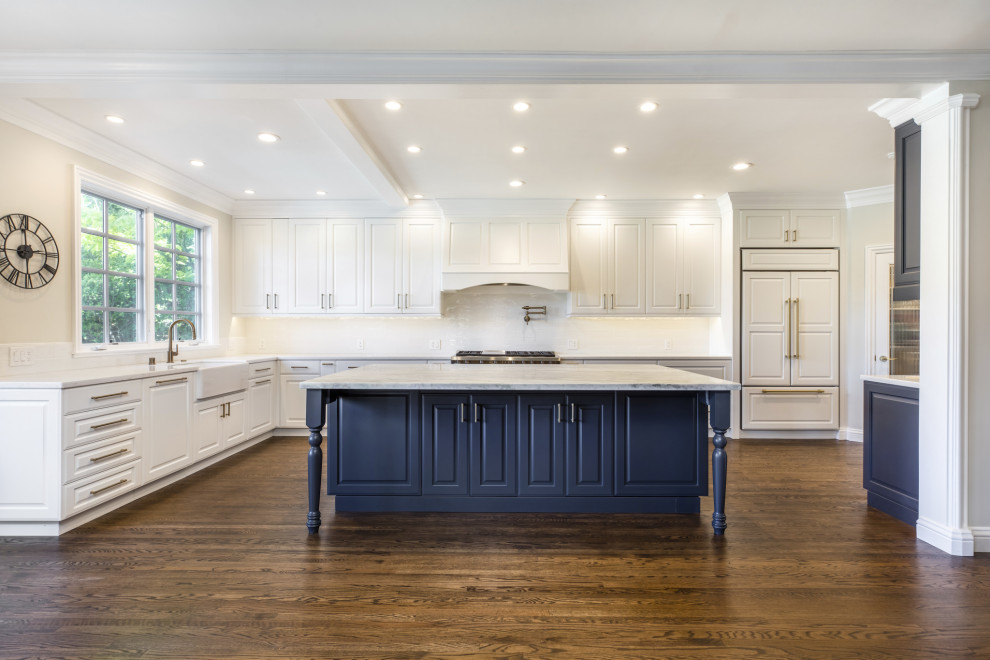 Design ideas for a large contemporary l-shaped kitchen in San Francisco with a farmhouse sink, raised-panel cabinets, white cabinets, marble benchtops, white splashback, panelled appliances, dark hardwood floors, with island, brown floor, white benchtop and ceramic splashback.