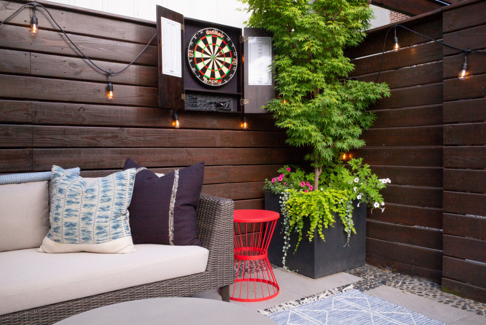 Small eclectic backyard patio in Austin with a container garden, concrete slab and an awning.