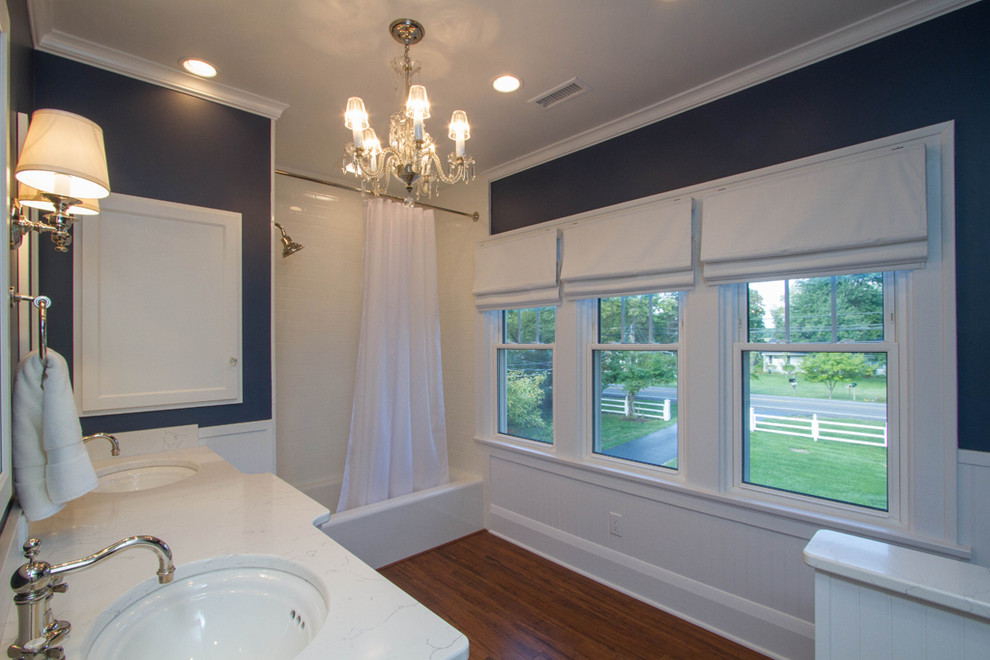Large transitional kids bathroom in Other with raised-panel cabinets, white cabinets, an alcove tub, a shower/bathtub combo, a two-piece toilet, white tile, ceramic tile, blue walls, bamboo floors, an undermount sink, granite benchtops, brown floor and a shower curtain.
