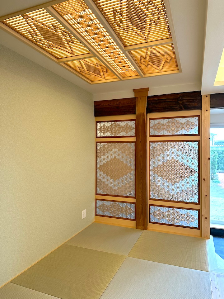 Mittelgroßes, Offenes Wohnzimmer mit weißer Wandfarbe, Tatami-Boden, grünem Boden, Kassettendecke und Tapetenwänden in Sonstige