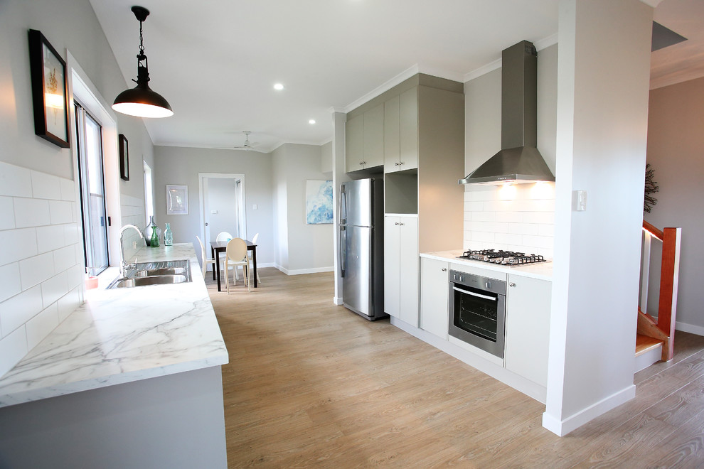 Inspiration for a small transitional galley open plan kitchen in Townsville with a double-bowl sink, flat-panel cabinets, grey cabinets, laminate benchtops, white splashback, ceramic splashback, stainless steel appliances, vinyl floors and no island.