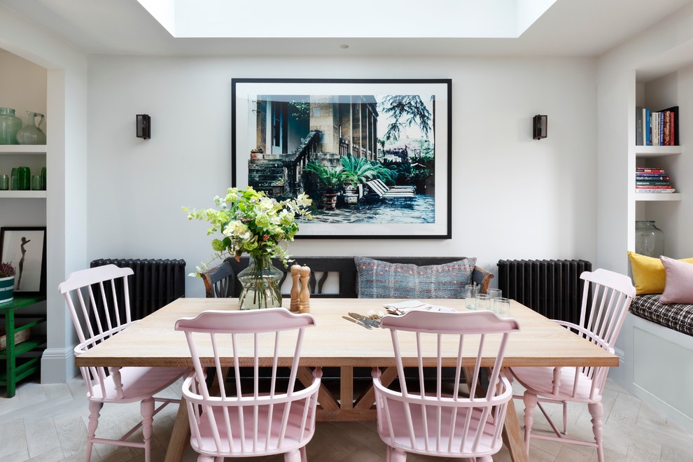 Mid-sized eclectic open plan dining in London with white walls and light hardwood floors.