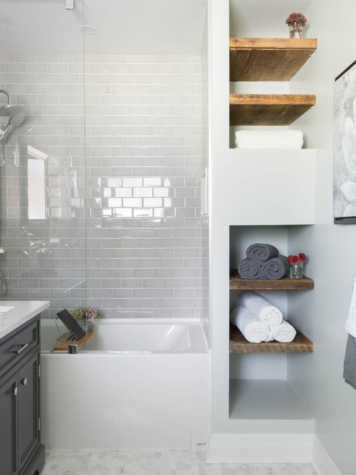 Mid-sized scandinavian 3/4 bathroom in Chicago with raised-panel cabinets, a drop-in tub, a shower/bathtub combo, a two-piece toilet, white tile, ceramic tile, white walls, mosaic tile floors, a drop-in sink, soapstone benchtops, multi-coloured floor, a sliding shower screen and grey cabinets.