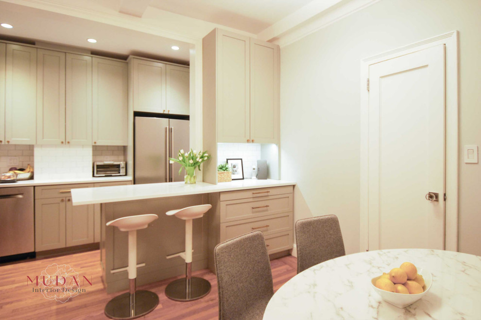 Small transitional galley medium tone wood floor eat-in kitchen photo with a farmhouse sink, shaker cabinets, gray cabinets, quartz countertops, ceramic backsplash, stainless steel appliances, a peninsula, white backsplash and white countertops