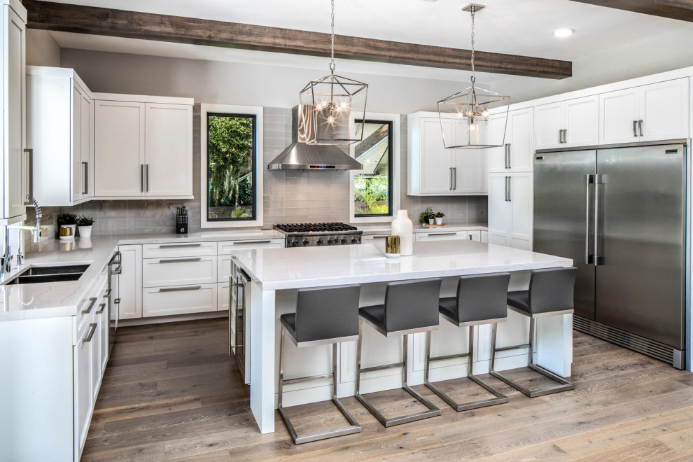 Inspiration for a large modern u-shaped eat-in kitchen in Tampa with a double-bowl sink, shaker cabinets, white cabinets, quartz benchtops, grey splashback, glass tile splashback, stainless steel appliances, medium hardwood floors, with island, brown floor, grey benchtop and exposed beam.