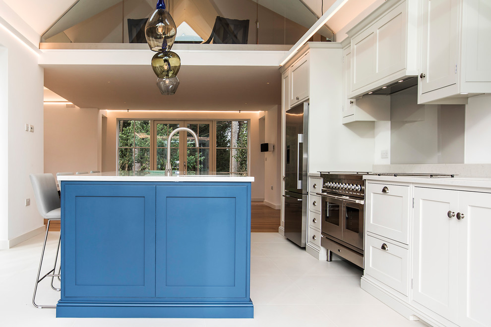 Design ideas for a large traditional single-wall open plan kitchen in Hampshire with a double-bowl sink, shaker cabinets, blue cabinets, quartzite benchtops, white splashback, stone slab splashback, stainless steel appliances, ceramic floors, with island, white floor and white benchtop.