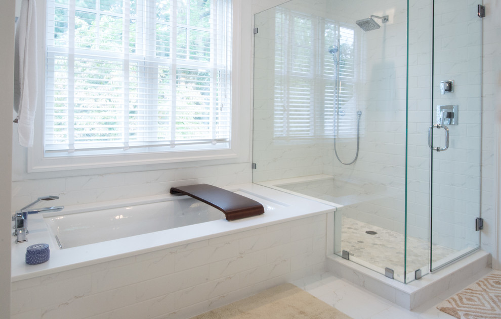 Photo of a mid-sized transitional master bathroom in Philadelphia with raised-panel cabinets, white cabinets, an undermount tub, a corner shower, white tile, porcelain tile, white walls, marble floors, an undermount sink, solid surface benchtops, white floor, a hinged shower door and white benchtops.