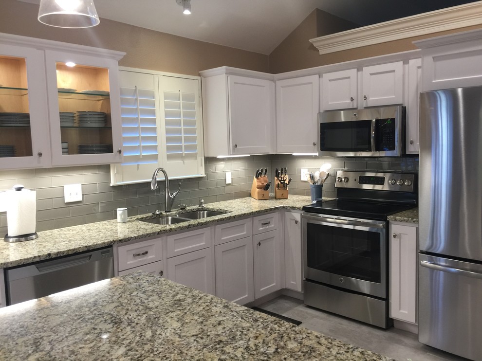 Example of a mid-sized transitional l-shaped porcelain tile eat-in kitchen design in Austin with an undermount sink, shaker cabinets, white cabinets, granite countertops, white backsplash, glass tile backsplash, stainless steel appliances and an island