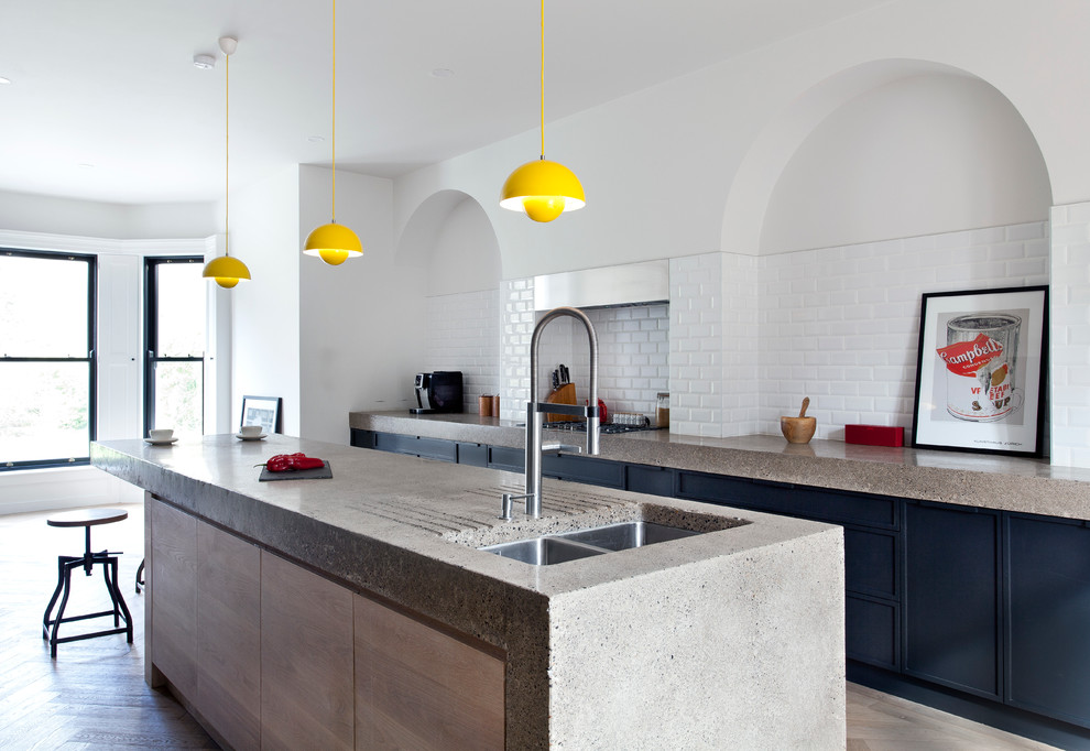 Inspiration for a contemporary galley kitchen in Dublin with flat-panel cabinets, black cabinets, concrete benchtops, light hardwood floors and with island.