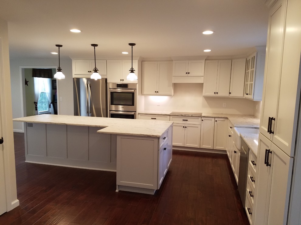 Mid-sized transitional l-shaped dark wood floor and brown floor eat-in kitchen photo with a farmhouse sink, shaker cabinets, white cabinets, granite countertops, white backsplash, subway tile backsplash, stainless steel appliances and an island