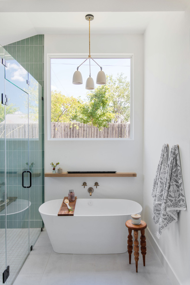 Modelo de cuarto de baño abovedado clásico renovado con bañera exenta, ducha empotrada, paredes blancas, suelo gris y ducha con puerta con bisagras