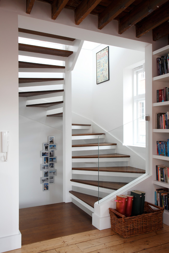 Photo of a large contemporary wood spiral staircase in London with open risers and brick walls.