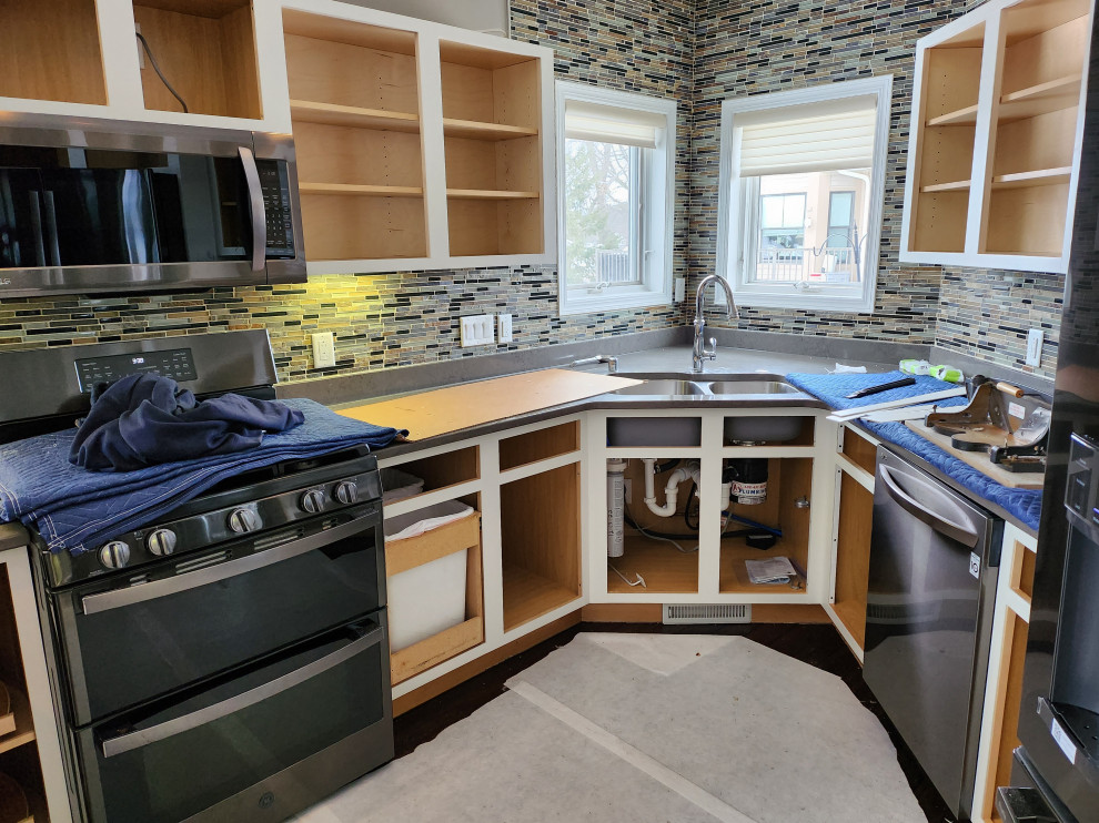 Mid-sized transitional u-shaped dark wood floor and brown floor open concept kitchen photo with an undermount sink, shaker cabinets, yellow cabinets, quartzite countertops, brown backsplash, glass tile backsplash, stainless steel appliances, a peninsula and gray countertops