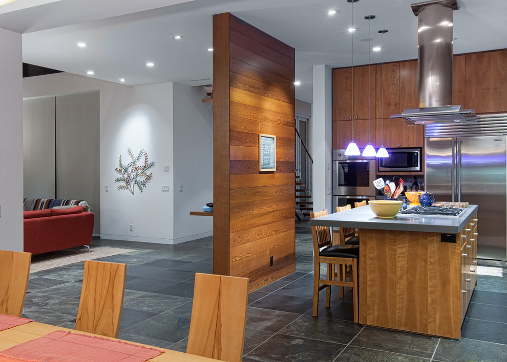 Photo of a large contemporary l-shaped eat-in kitchen in San Diego with an undermount sink, flat-panel cabinets, medium wood cabinets, solid surface benchtops, grey splashback, slate splashback, stainless steel appliances, slate floors, with island and grey floor.